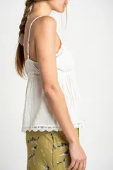 Blusa blanca de algodón con tirantes finos y escote en V. Presenta detalles de encaje en el escote y en el ruedo, y cierre frontal con botones.