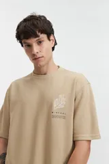 Remera beige de manga corta con textura y corte oversize. Presenta un pequeño bordado en relieve en el pecho.