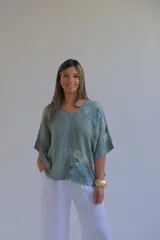 Blusa verde seco con estampado floral, confeccionada en lino italiano. Presenta escote en V en frente y espalda, y mangas murciélago.