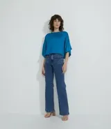 Blusa celeste de viscosa con textura satinada, cuello redondo, manga corta con sisa desplazada y abertura en la espalda.