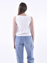 Blusa blanca sin mangas con escote en V y detalle de nudo en el centro.