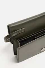 Bandolera color verde oliva con correa fina ajustable. Cierre con solapa e imán. Incluye bolsillo interno y charm decorativo.