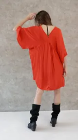 Vestido corto color beige, de raso, con escote en V y mangas 3/4. Corte holgado.