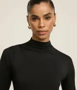 Blusa color beige de poliéster con cuello alto, mangas largas y fruncidos delanteros.