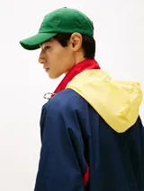 Campera Tommy Jeans azul marino con interior amarillo, cierre con botones a presión, cuello alto, cordón ajustable en la cintura, dos bolsillos delanteros y logo de la marca en la manga.