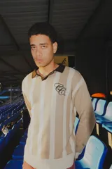 Sweater de punto a rayas verticales azules y blancas, con cuello polo negro y logo bordado en el pecho.