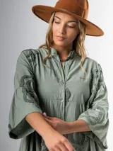 Vestido italiano 100% algodón, color verde oliva, corte midi y calce amplio. Tiene cuello mao y apliques de flores con textura.