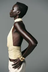 Top color crema con cuello halter, espalda descubierta, detalle de frunces y pieza metálica en forma de sol en el delantero.