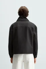 Sobrecamisa negra de corte cuadrado, con cuello solapa, manga larga con puños abotonados, bolsillos tipo parche en el pecho, bolsillos laterales y cierre frontal con botones.