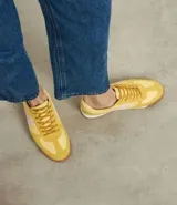 Championes amarillos con detalles en lila, de estilo vintage con punta redonda, cordones y recortes contrastantes. Suela marrón con base blanca.