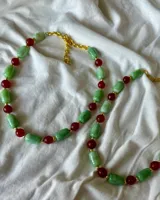 Collar corto con cuentas de piedra verde, cuentas de piedra roja y detalles dorados.