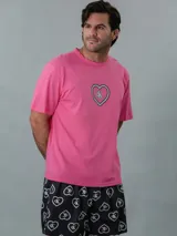 Conjunto de pijama Calvin Klein de dos piezas. Incluye una remera rosa de manga corta con cuello redondo y logo estampado en el pecho, y un short negro con estampado de corazones y logo de la marca.