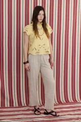 Blusa color coral o terracota con bordado calado floral en tono beige claro. Presenta cuello alto con volado y mangas cortas abullonadas.