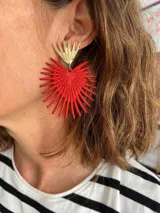 Aros colgantes con forma de corazón rojo con diseño de rayos y base dorada.