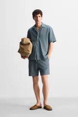 Bermuda azul de tejido con mezcla de algodón, corte relaxed fit, cintura elástica ajustable con cordón, bolsillos delanteros y detalle de bolsillo trasero de vivo.