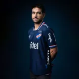 Camiseta de fútbol Umbro del Club Nacional de Football, modelo Away 2 2024. Diseño azul con detalles en blanco y rojo en cuello y mangas. Incluye logo de Umbro, escudo del club y sponsor Antel en el frente.