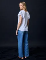 Blusa blanca texturada de poliéster, rayón y elastano, con mangas cortas con volados en capas y aplique de puntilla.
