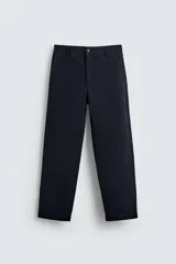 Pantalón chino color beige, de corte recto y tiro medio. Confeccionado en tejido de algodón con elasticidad, con bolsillos laterales y traseros de vivo. Cierre frontal con cremallera y botón.