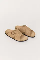 Sandalias bajas color beige con tiras cruzadas y hebilla lateral. Suela de corcho y base de goma.