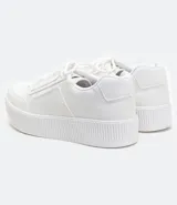 Zapatilla deportiva blanca de mujer, estilo casual, con cordones satinados y suela de plataforma gruesa con textura acanalada.