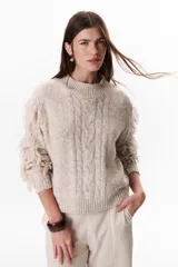 Sweater color beige de tejido de punto con cuello redondo y mangas largas con flecos.