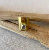 Anillo ancho de bronce color dorado con una piedra cuadrada color gris.