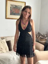 Vestido corto de lentejuelas color verde oliva, con escote en V, breteles finos cruzados en la espalda, cut-outs laterales y volado en el ruedo.