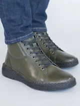 Botín de cuero color verde oscuro con sistema de ajuste mediante cordones negros y suela de poliuretano flexible. Presenta una caña de 10 cm y un taco de 3 cm, ofreciendo un diseño ergonómico y confortable para el uso diario.
