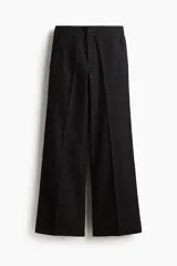 Jean de denim de algodón negro con leve stretch, corte ajustado de cintura a muslo y acampanado desde la rodilla al bajo. Modelo de tiro alto con cierre, botón y corchete ocultos. Bolsillos al bies y bolsillos decorativos atrás.