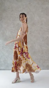 Vestido largo de seda plisada estampada con flores grandes en tonos marrón, amarillo y violeta. Diseño de solera con tirantes finos.