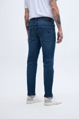 Jean de denim azul oscuro, corte slim fit, entallado en caderas y muslos, ajustado levemente desde la rodilla hasta el tobillo.