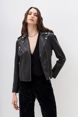 Campera confeccionada en cuero, de corte motoquero, con charreteras y cierres metálicos plateados en puños y bolsillos.