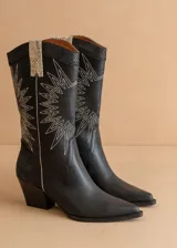 Botas texanas de cuero sintético negro con caña media, puntera fina y taco bajo. Presentan apliques con diseño reptil en la parte superior y bordados blancos con forma de rayos de sol.