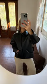 Campera negra de ecocuero con cierre frontal y bolsillos laterales con detalle de ojales metálicos.