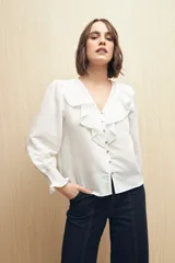 Camisa blanca a rayas verticales, con escote en V, mangas 3/4 con puños elastizados y volados.