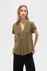 Blusa color crudo de viscosa, corte holgado, con cuello en v y cierre frontal con dos botones de madera.