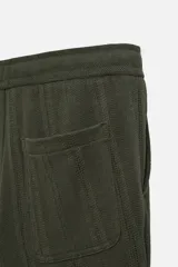 Pantalón verde oscuro con textura de rayas verticales, corte relaxed fit, cintura elástica ajustable con cordón, bolsillos delanteros y bolsillo trasero de parche.
