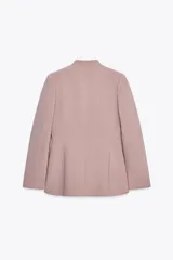 Blazer color rosa palo, sin solapa, de corte recto y manga larga. Presenta bolsillos de ojal en el delantero y cierre frontal con gancho metálico.