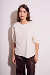 Remera color crema de algodón peinado, con mangas 3/4 abullonadas y corte ajustado al cuerpo.