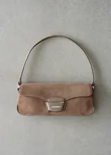 Bolso de hombro mediano confeccionado en piel de serraje color beige, con diseño rectangular y cierre de solapa con hebilla metálica central.