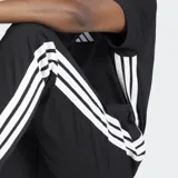 Pantalón de jogging Adidas Essentials con corte clásico, color negro con tres rayas blancas a los costados, cintura elástica con cordón de ajuste, bolsillos frontales y logo bordado.