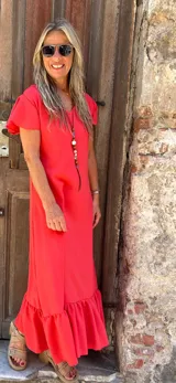 Vestido midi de seda color rojo, con escote en V, mangas cortas con volados y un amplio volado en el ruedo.