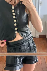 Short negro de cuero ovino con bordados y volados en el ruedo.