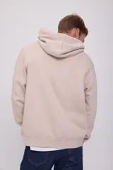 Canguro color crema con capucha, cordones ajustables, bolsillo tipo canguro y puños y bajo acanalados. Estampado con texto en el pecho.