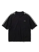 Chomba de tejido de punto cerrado color blanco, con cuello polo y mangas cortas. Presenta un bordado sutil en el frente y tres franjas negras en los hombros.