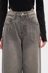 Pantalón gris de jean de corte recto y tiro alto, con detalles de ojales metálicos en la parte superior.
