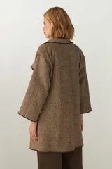 Tapado marrón de largo medio, abierto, con cuello y envivado. Hecho 100% en Uruguay con tela 100% lana fina sin teñir, diseñada exclusivamente por Don Baez.