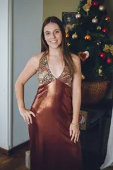 Vestido largo color marrón cobrizo con escote en V, cut outs laterales bajo el busto y breteles finos que se cruzan y atan en la espalda. Presenta un top con estampado abstracto en tonos marrones y dorados.