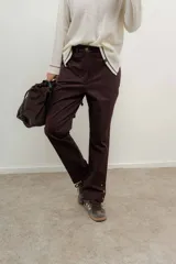 Pantalón de jean azul oscuro de corte recto con detalle de botones dorados en el tobillo.