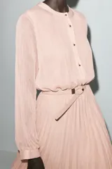 Vestido midi de color rosa pálido con falda plisada, cuello redondo, manga larga y cinturón fino.